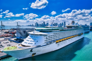 Navio de cruzeiro atracado em porto sob céu ensolarado, simbolizando o início da temporada de cruzeiros e as viagens em família com crianças.